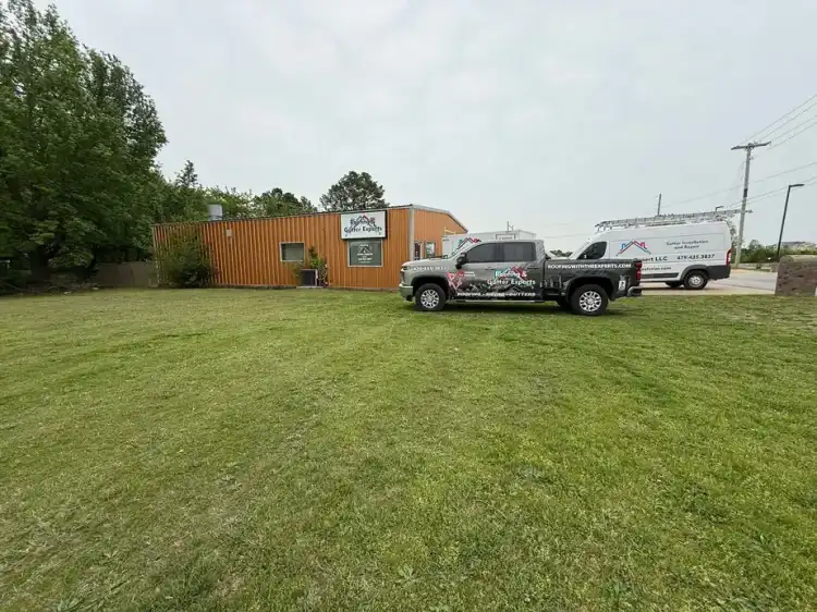 The Roofing & Gutter Experts office at 707 S 48th St in Springdale, with the wrapped company pickup and the gutter van parked on the lot