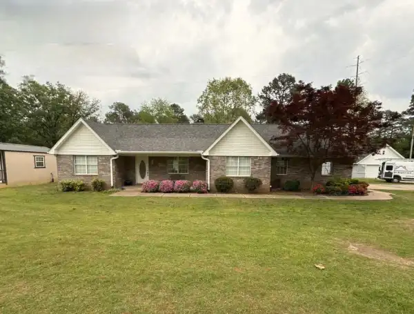 A brick-and-siding ranch with a finished roof under an overcast sky