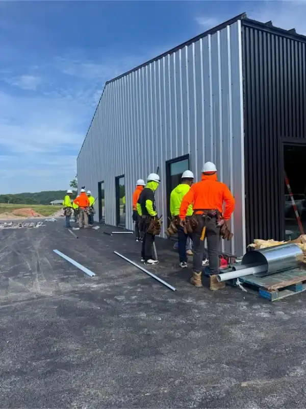 A crew in hi-vis standing beside a new black and silver metal building