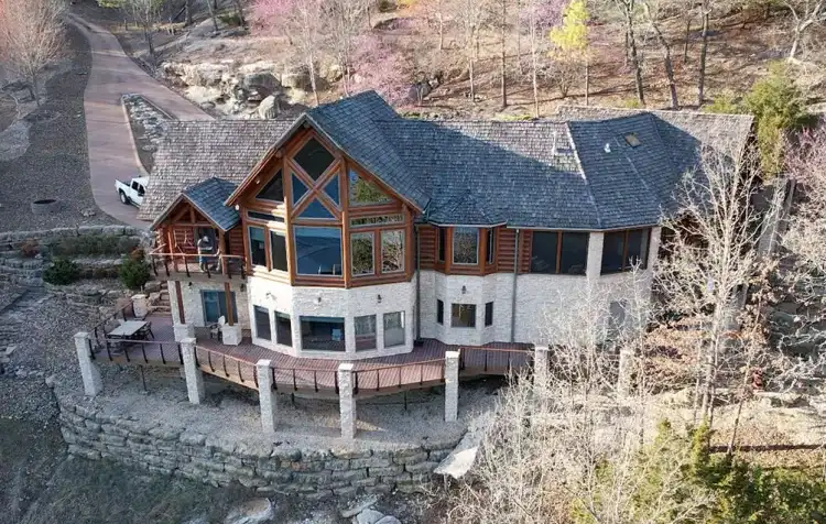 A finished log and stone lake home with a new slate-look shingle roof on a wooded bluff in Northwest Arkansas