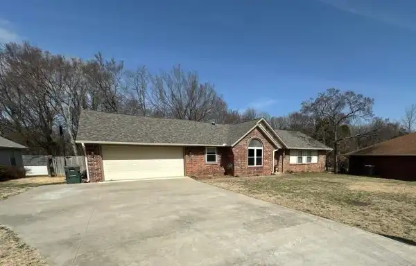 A brick ranch with a finished roof and a wide drive in Northwest Arkansas