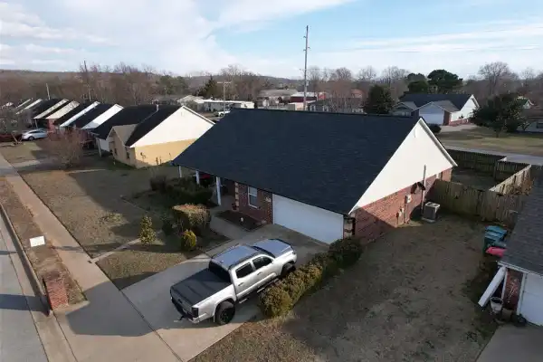A finished home with a new charcoal shingle roof and a grey pickup in the driveway